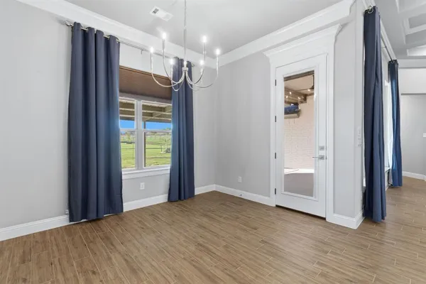 a view of empty room with wooden floor and window
