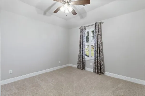 an empty room with a ceiling fan and window