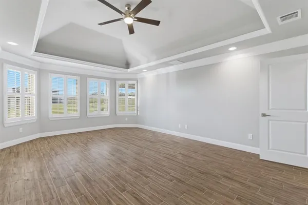 a view of empty room with wooden floor and fan