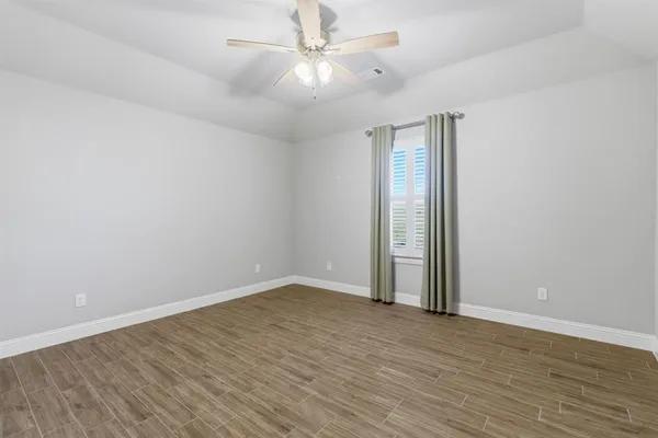 an empty room with wooden floor and fan