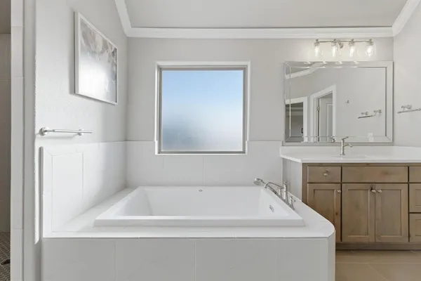 a bathroom with a tub a sink and mirror