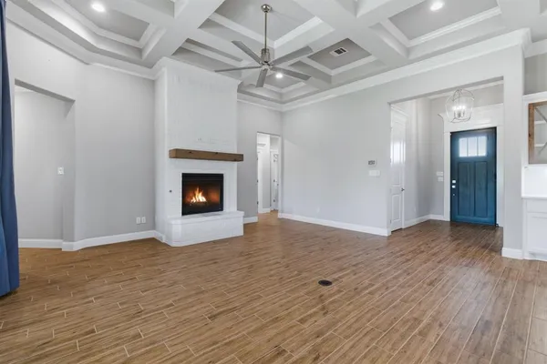 a view of an empty room with wooden floor fireplace and a window