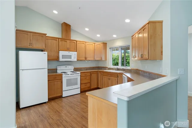 a kitchen with stainless steel appliances granite countertop white cabinets sink and dishwasher with wooden floor