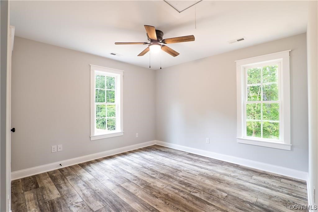 0 Howerton Road Dunnsville, VA 22454 - Photo 8 of 11 an empty room with wooden floor ceiling fan and windows