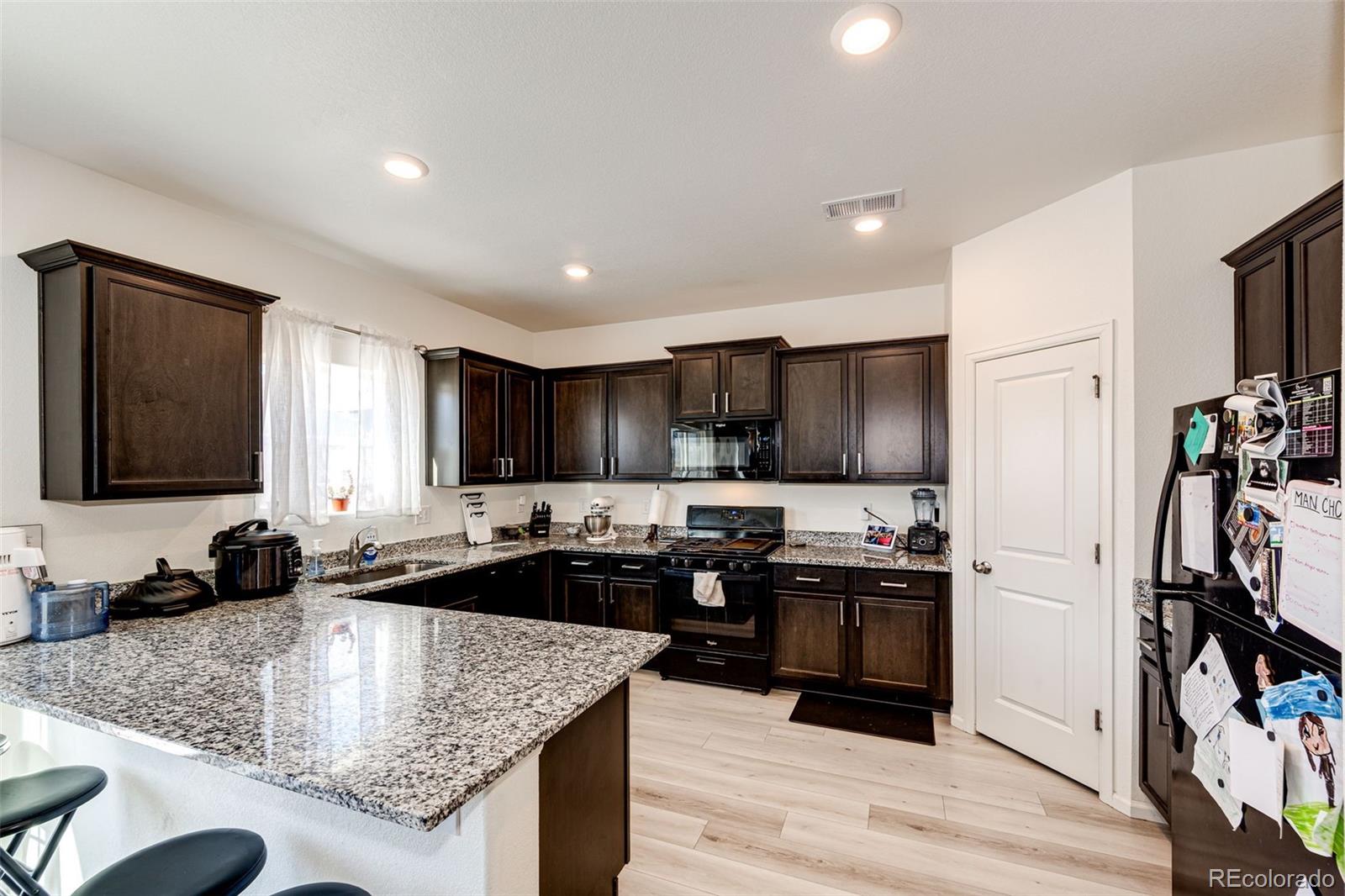 325 Walnut Street Bennett, CO 80102 - Photo 9 of 22 a kitchen with stainless steel appliances granite countertop a sink stove and refrigerator