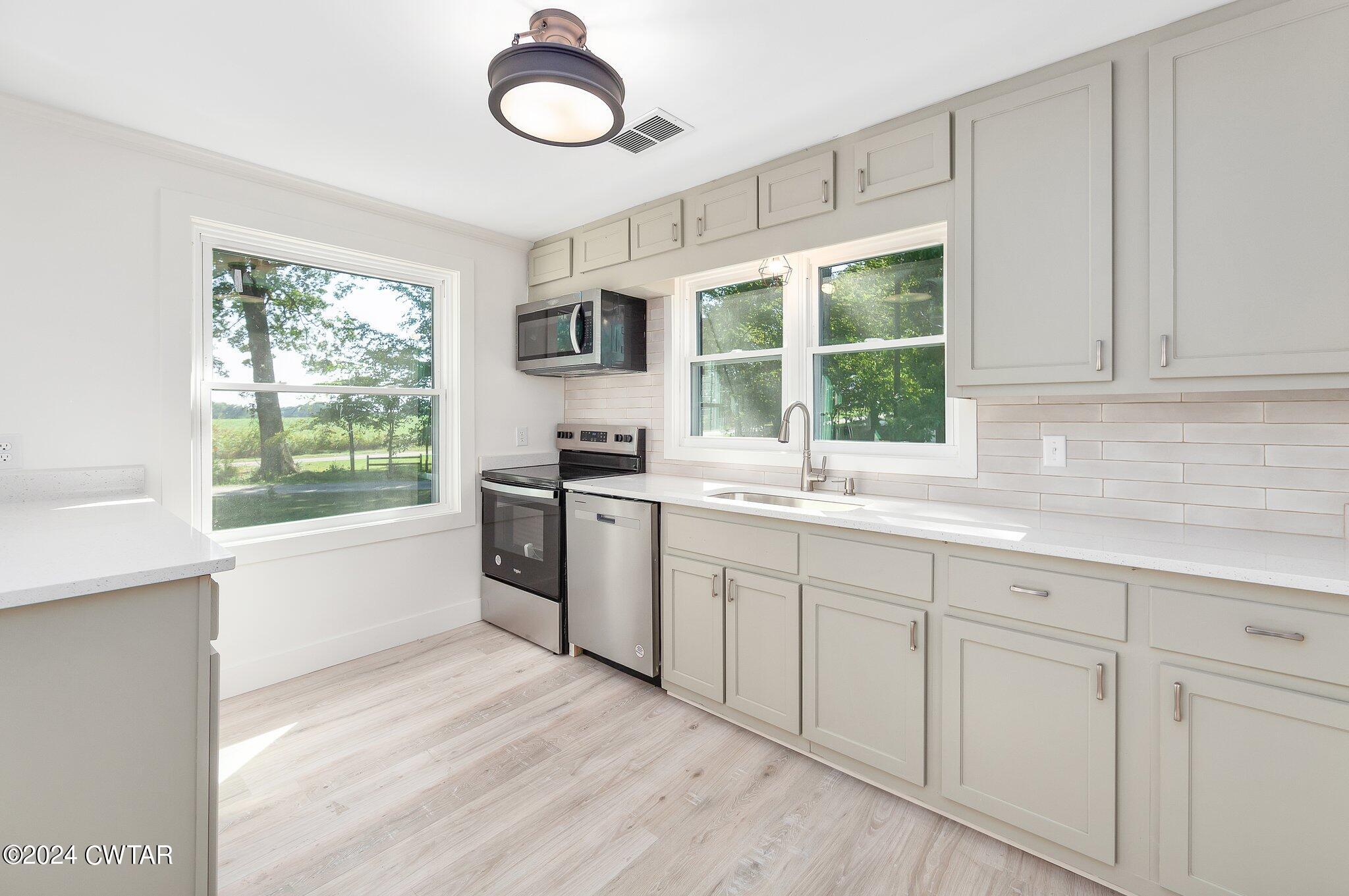 1396 Old Bells Road Jackson, TN 38305 - Photo 12 of 26 a kitchen with white cabinets a window and a sink