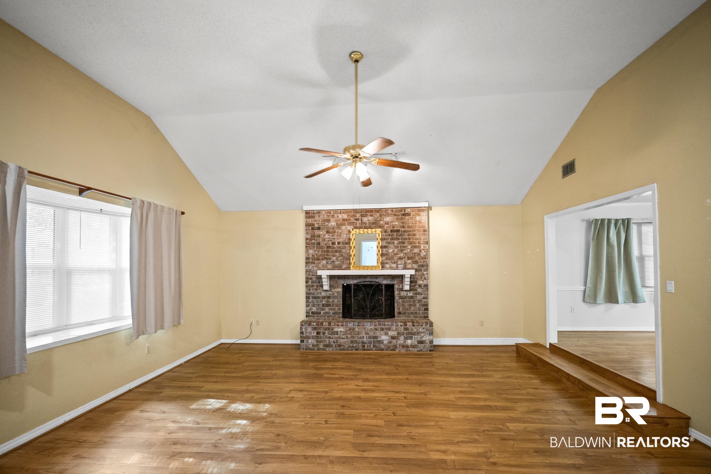 123 Dunbar Loop Daphne, AL 36526 - Photo 4 of 33 Unfurnished living room featuring a brick fireplace, wood finished floors, ceiling fan, and lofted ceiling