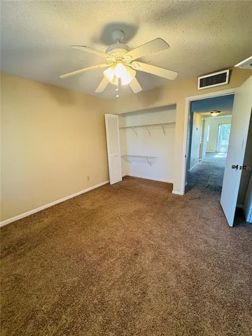 an empty room with a chandelier fan and windows