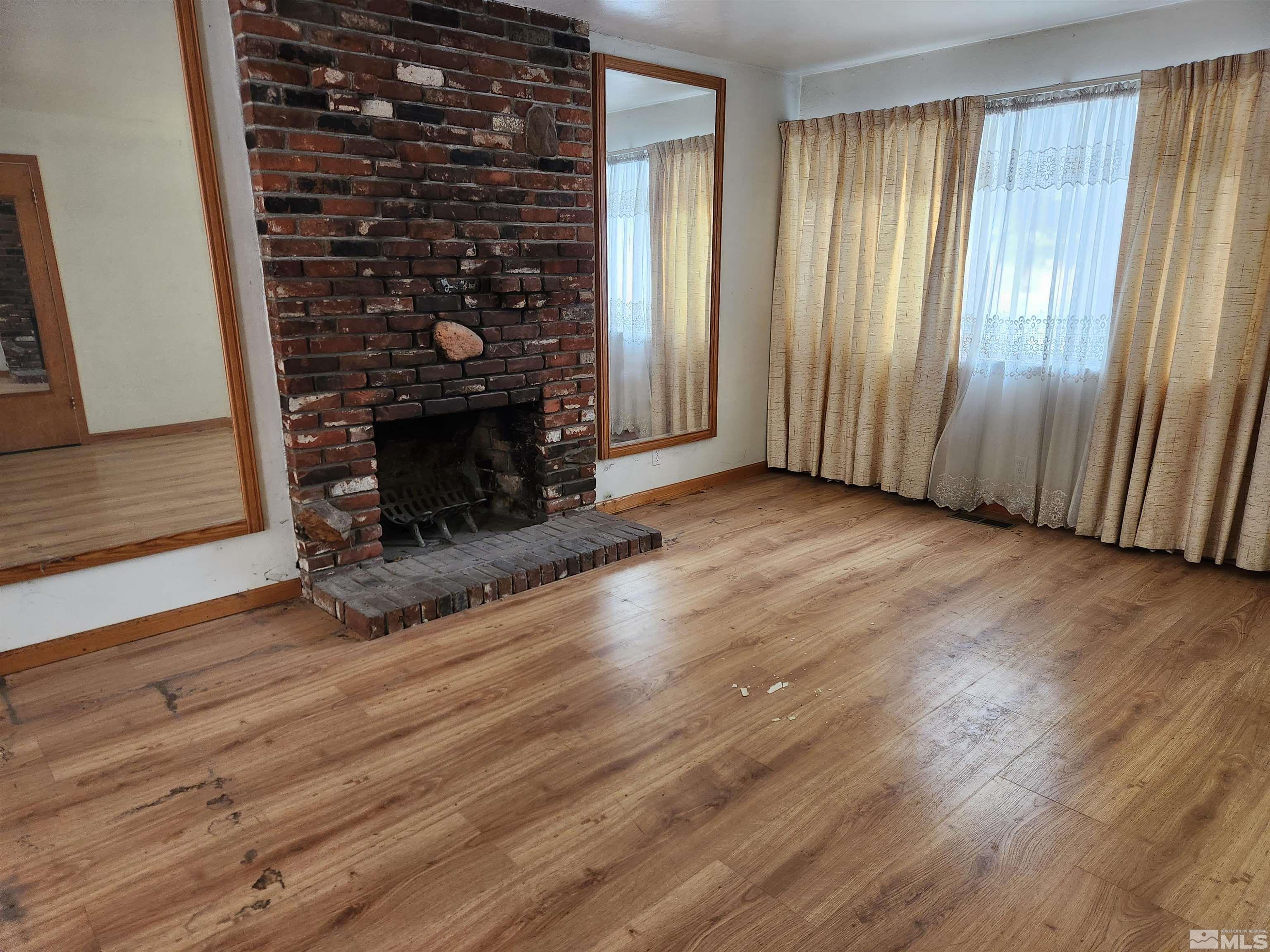 1610 West 7th Street Reno, NV 89503 - Photo 3 of 14 an empty room with wooden floor fireplace and windows