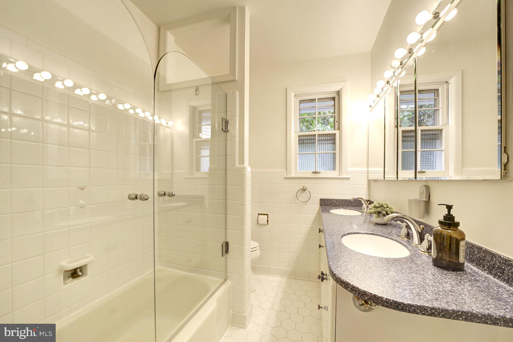 2824 Ellicott Street Northwest Washington, DC 20008 - Photo 39 of 47 a bathroom with a granite countertop sink a mirror and a shower