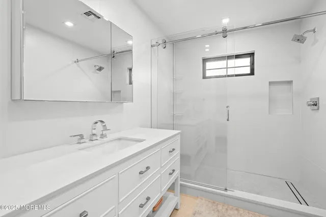 a bathroom with a sink shower and a mirror
