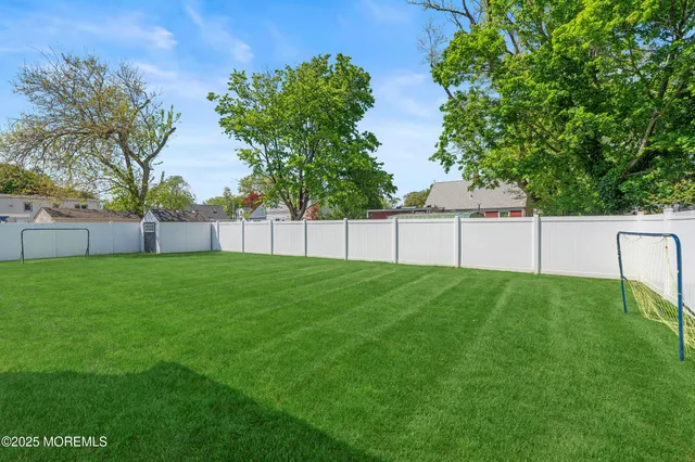 a view of a backyard with grass and white fence