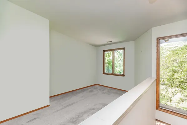 a view of an empty room with window and chandelier fan