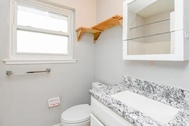 a bathroom with a sink a toilet and a window