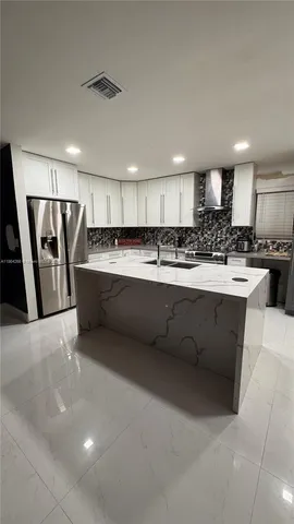 a kitchen with stainless steel appliances granite countertop a sink a stove a refrigerator cabinets and a counter top space