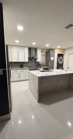 a kitchen with stainless steel appliances kitchen island granite countertop a stove a sink and a refrigerator