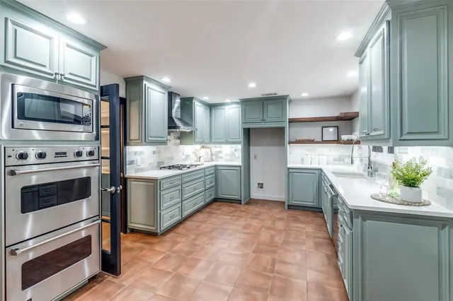 a kitchen with stainless steel appliances kitchen island granite countertop a stove a sink and a microwave