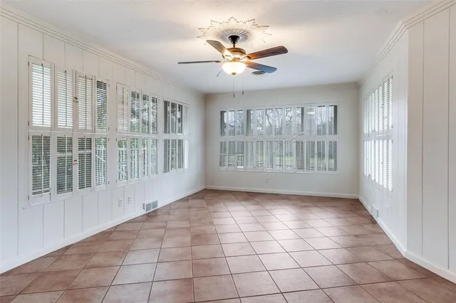 a view of an empty room with a window and chandelier fan