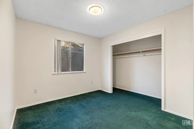 a view of an empty room with closet and a window