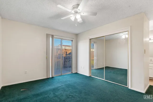 a view of an empty room with closet and a ceiling fan