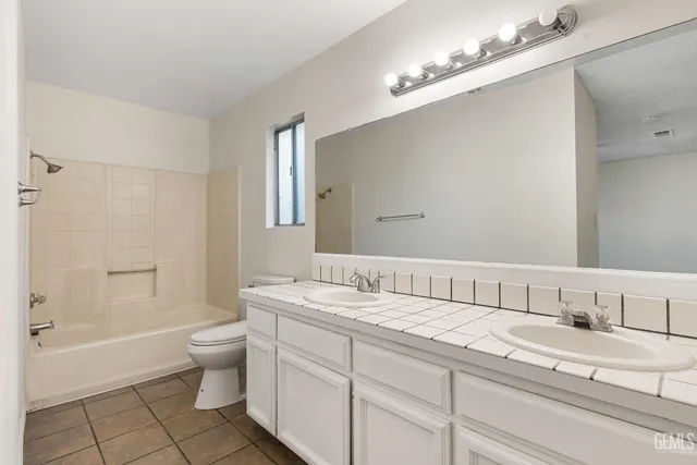 a spacious bathroom with a double vanity sink a toilet and a mirror
