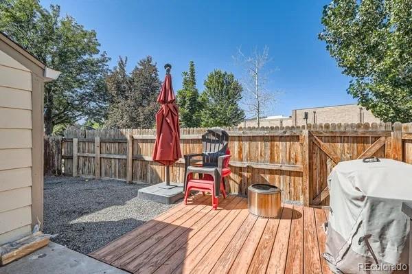 9640 West Chatfield Avenue, Unit F Littleton, CO 80128 - Photo 7 of 7 a view of a roof deck with table and chairs a barbeque with wooden floor and fence