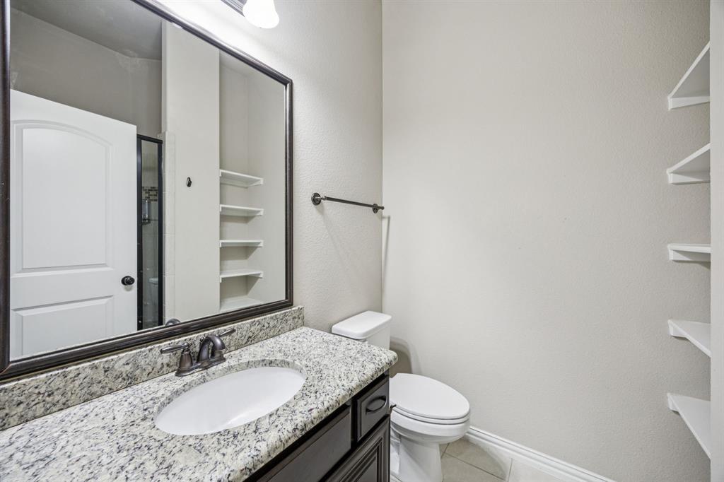 7205 Joshua Tree Trail McKinney, TX 75070 - Photo 12 of 32 a bathroom with a granite countertop sink a toilet and a mirror