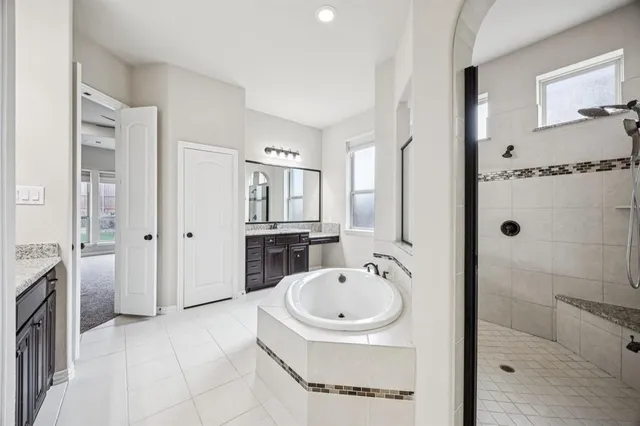 a spacious bathroom with a tub shower and mirror