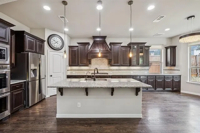 a view of kitchen with stainless steel appliances granite countertop stove top oven and refrigerator