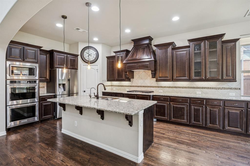 7205 Joshua Tree Trail McKinney, TX 75070 - Photo 7 of 32 a kitchen with stainless steel appliances granite countertop a stove and cabinets