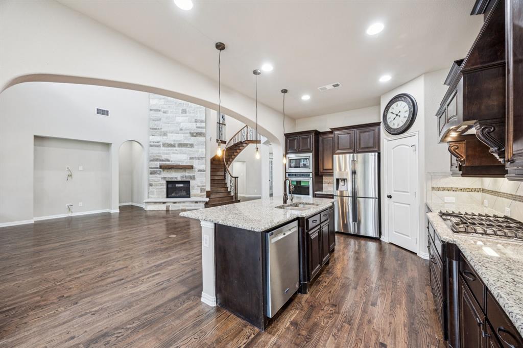 7205 Joshua Tree Trail McKinney, TX 75070 - Photo 32 of 32 a kitchen with granite countertop a stove top oven a clock and wooden floor