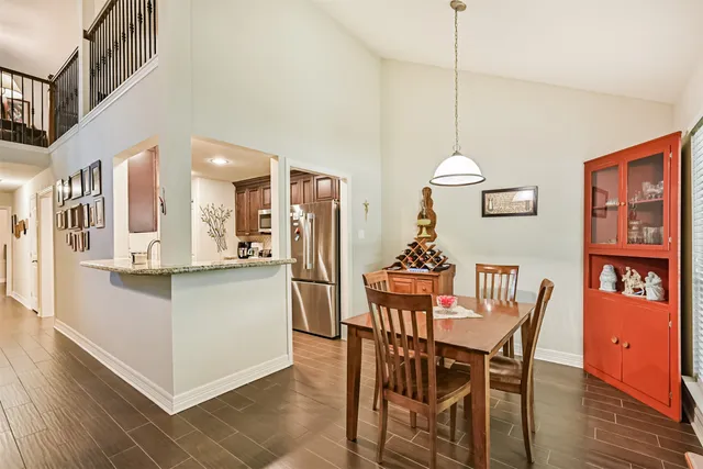 a kitchen with stainless steel appliances kitchen island granite countertop a table chairs and a refrigerator