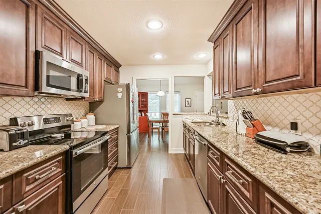 a kitchen with granite countertop lots of counter top space a sink and stainless steel appliances