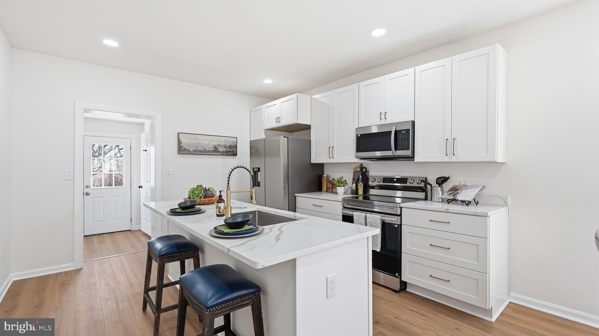a kitchen with a sink a stove a refrigerator and white cabinets with wooden floor