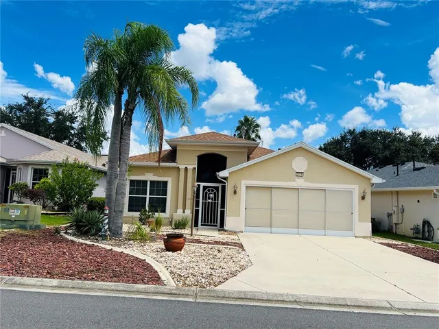 a front view of a house with garage and plants