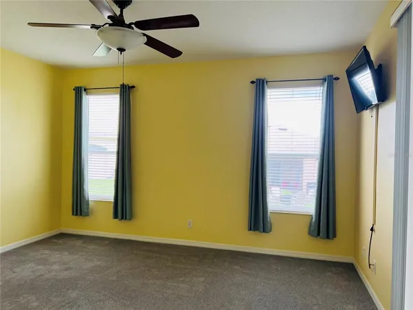 an empty room with windows and fan