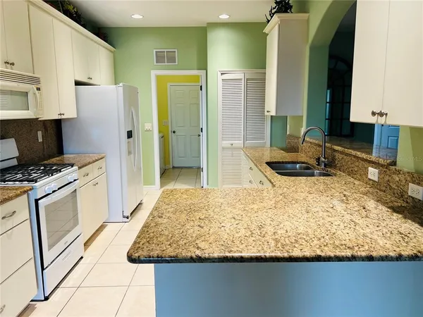 a kitchen with kitchen island granite countertop a sink stove and refrigerator