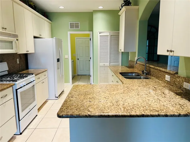 a kitchen with kitchen island granite countertop a sink stove and refrigerator