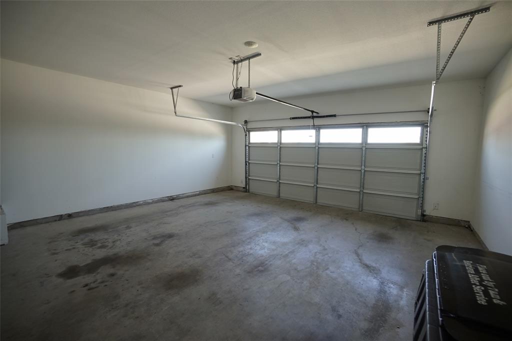 1764 Palladio Loop Princeton, TX 75407 - Photo 14 of 40 Spacious garage featuring a sectional overhead door with upper transom window panels, concrete flooring, and an automatic garage door opener