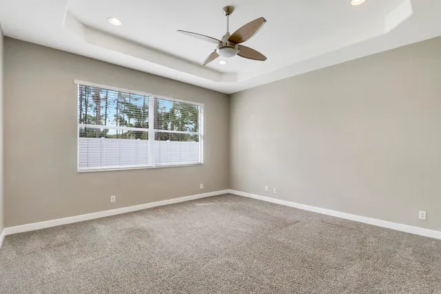 an empty room with a ceiling fan and windows