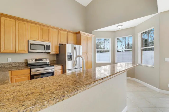 a large kitchen with granite countertop a refrigerator oven a sink a dining table and chairs