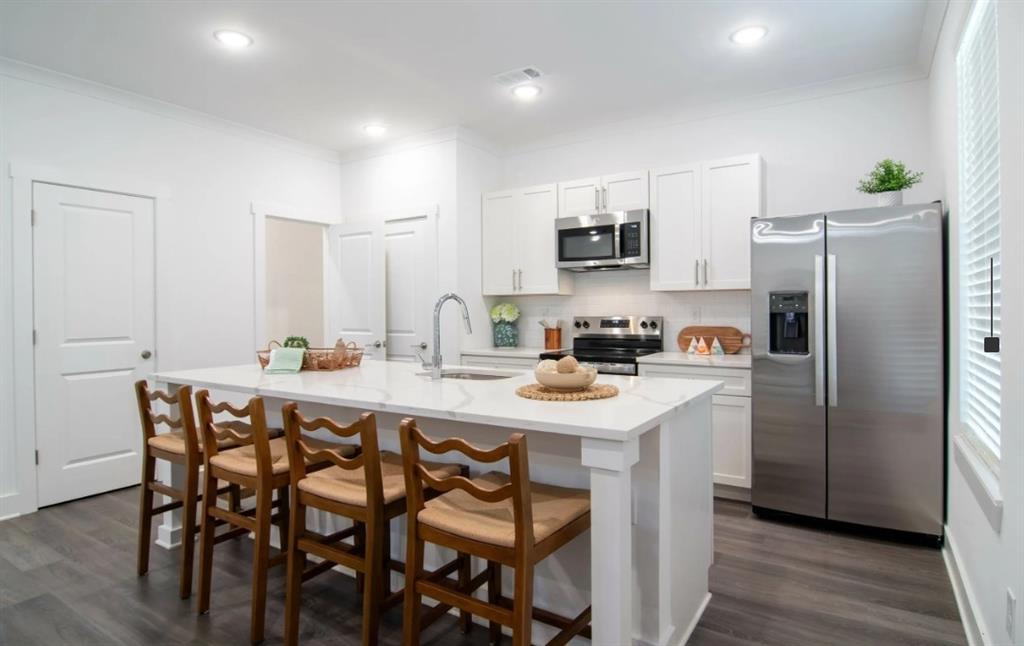 a kitchen with stainless steel appliances a table chairs refrigerator and microwave