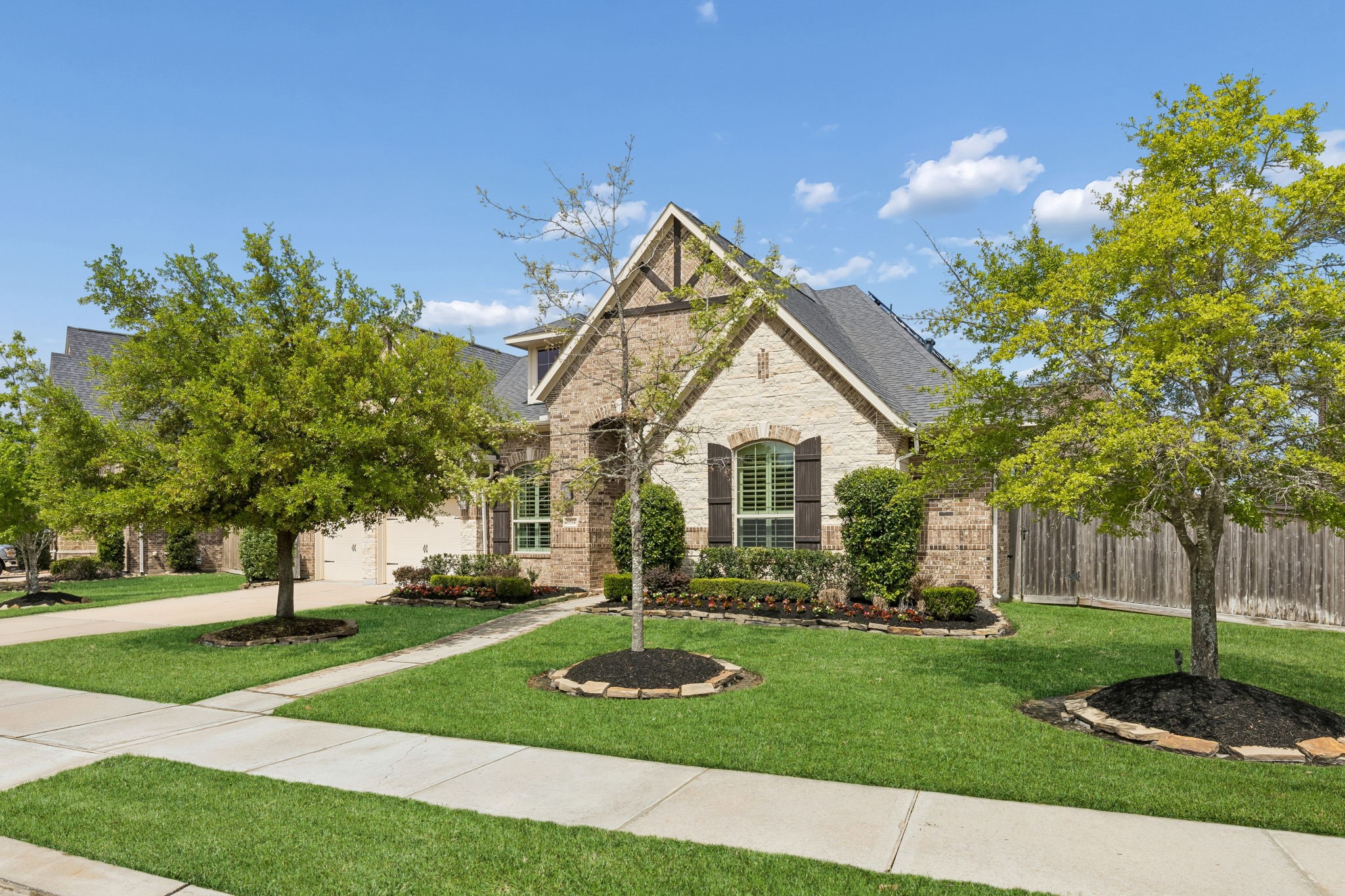 Welcome to 6514 Woodleaf Lake Loop, a stunning full-brick and stone one-story residence featuring a rare three-car tandem garage and meticulously designed landscaping.