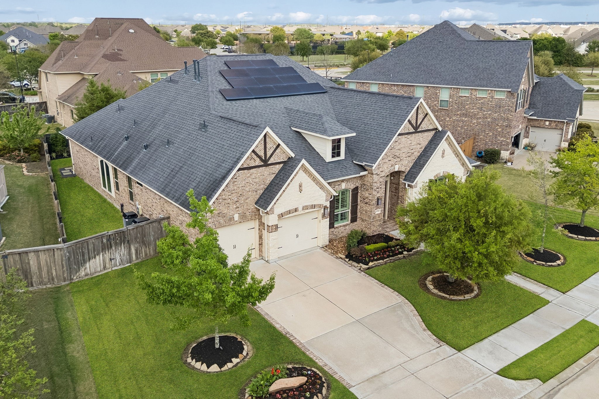 6514 Woodleaf Lake Loop Katy, TX 77493 - Photo 4 of 32 This dramatic aerial view highlights the home's impressive scale and its commitment to sustainability with solar panels. The perspective also showcases the rare three-car tandem garage and the meticulously maintained full-brick and stone architecture.