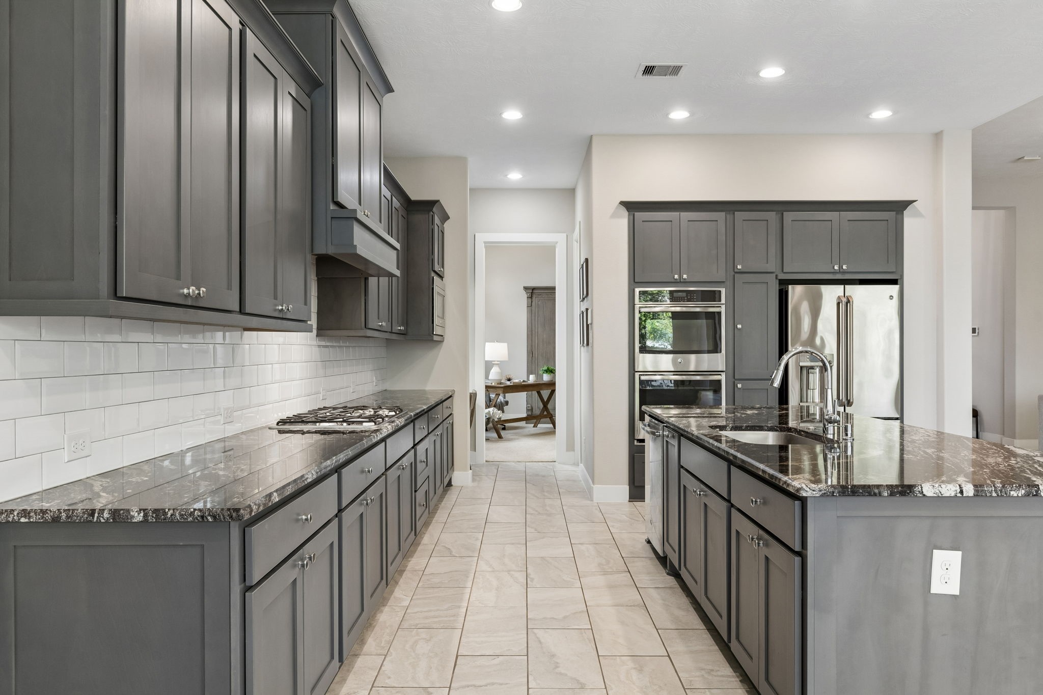 6514 Woodleaf Lake Loop Katy, TX 77493 - Photo 7 of 32 Designed for culinary excellence, the kitchen is finished with a classic subway tile backsplash and extensive granite counter space. The layout includes a deep walk-in pantry and soft-closing hardware for ultimate organization.