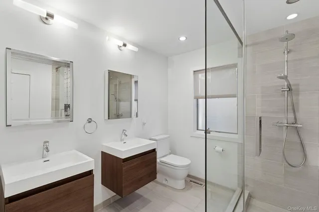a bathroom with a double vanity sink toilet and shower