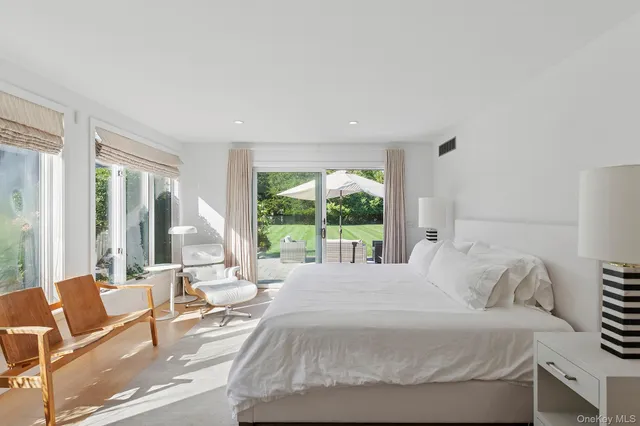 a bedroom with a bed and large windows