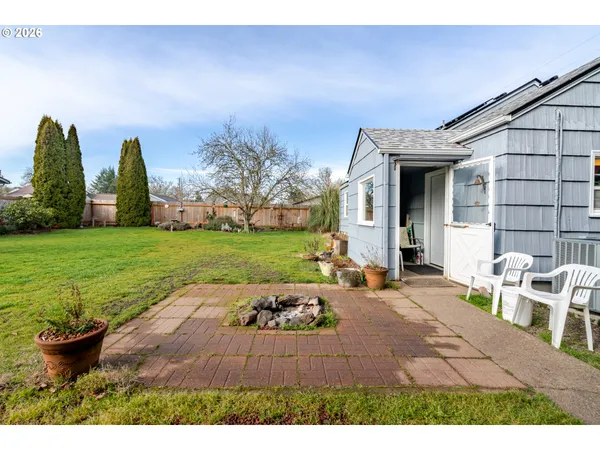 a view of a backyard with table and chairs potted plants and large tree