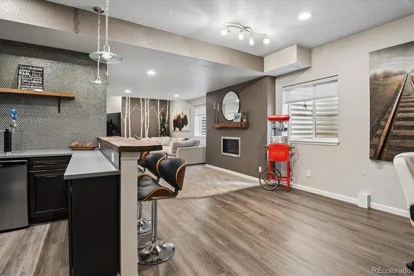 a kitchen with stainless steel appliances kitchen island granite countertop a stove a refrigerator a sink a dining table and chairs with wooden floor