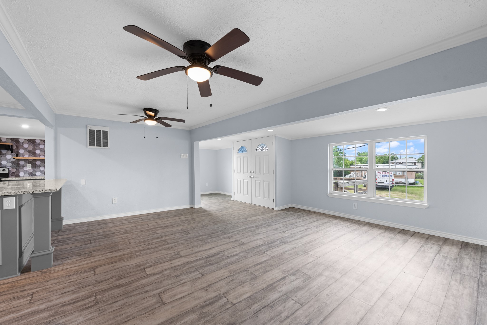 2534 Bastrop Angleton, TX 77515 - Photo 6 of 50 Open-concept living space with updated wood-look flooring, recessed lighting, and large windows that fill the home with natural light. The spacious layout flows seamlessly into the kitchen area, creating an ideal setting for everyday living and entertaining.